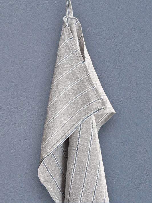 Stripet kjøkkenhåndkle i 100 % lin i natur med blå striper hengt på vegg.