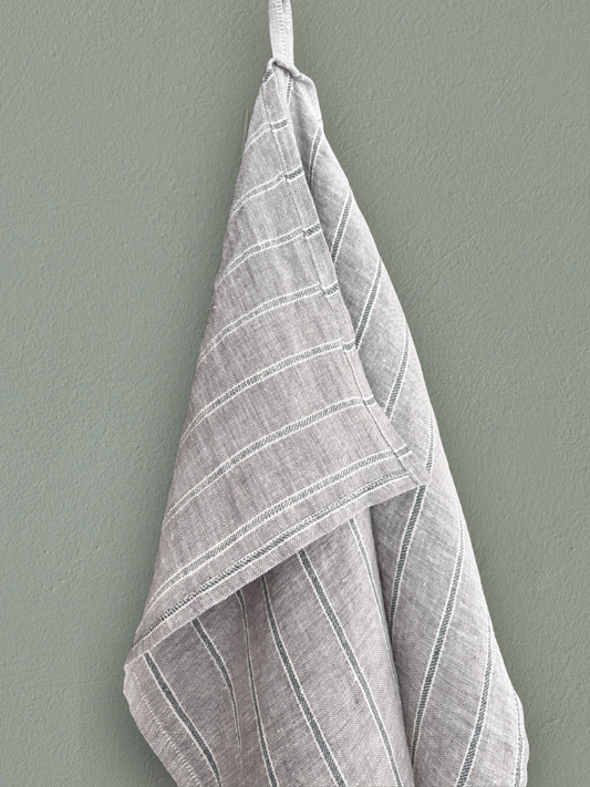 Kjøkkenhåndkle i 100 % lin med grønne striper hengt på vegg.