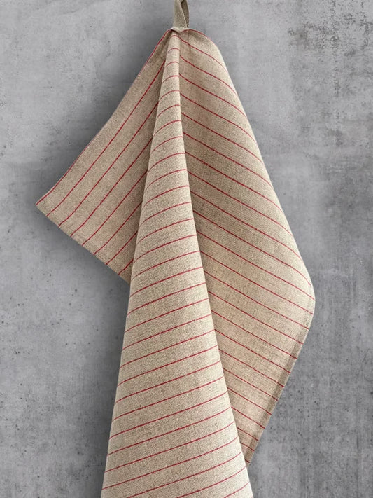 Linhåndkle i naturfarge med brede røde striper, hengende på betongvegg.
