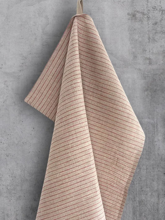 Linhåndkle i naturfarge med smale, røde striper, hengt på en betongvegg